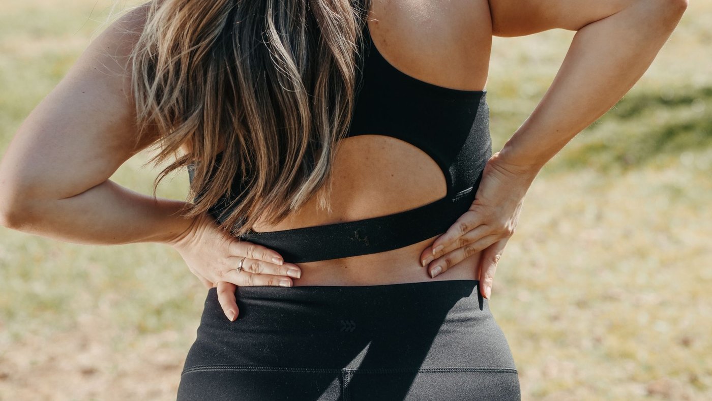 Hands pressing on an aching lower back